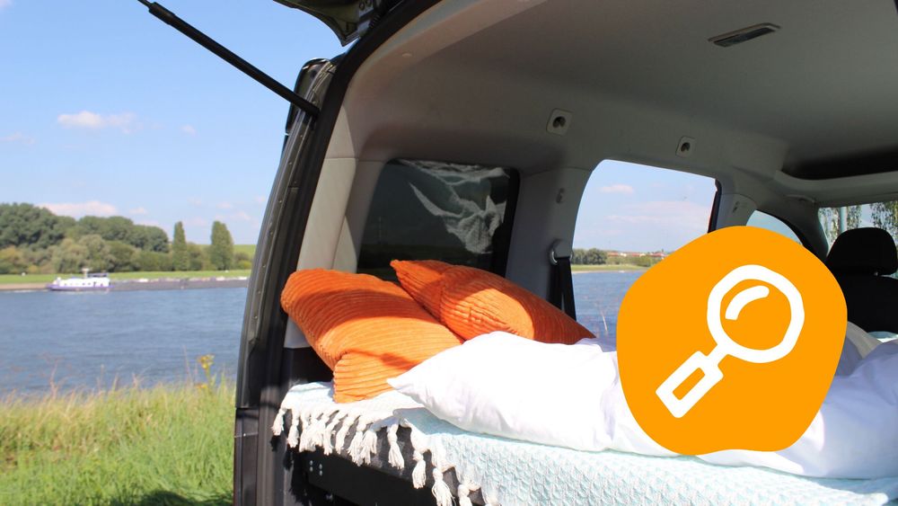 Offene Minicamper mit Bett steht am Fluss.